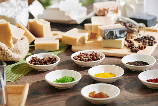 Ingrédients naturels pour la fabrication de savon artisanal : épices, argile, fleurs séchées et colorants naturels disposés dans des bols, mettant en avant l'authenticité des composants d'un savon fait main.